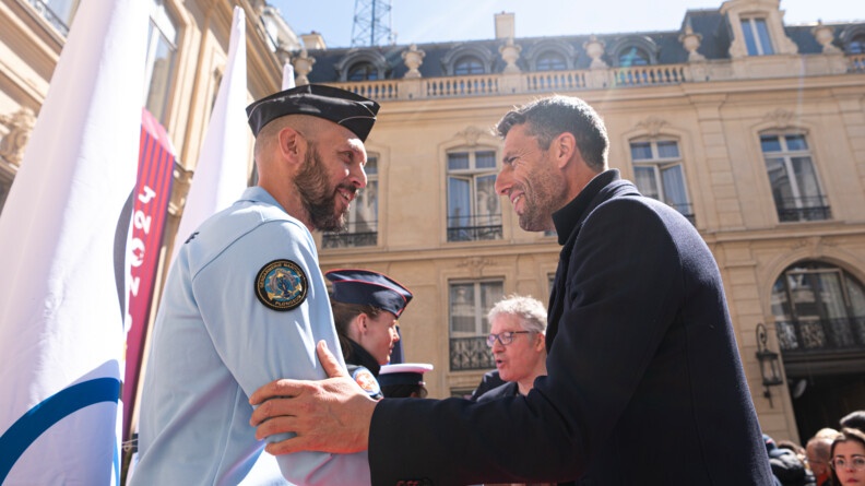 Photo de Hugues Duboscq en tenue de gendarme et de Tony Estanguet qui se serrent la main.