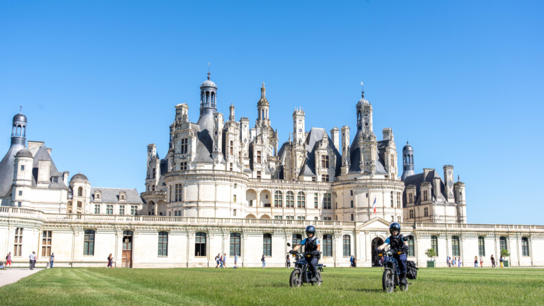 2 nouvelles motos électriques tout terrain de marque UBCO devant le Château de Chambord