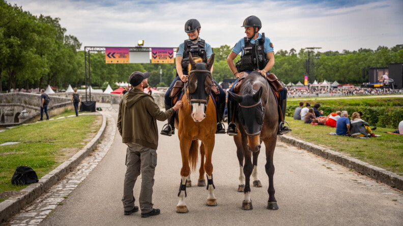 Deux gendarmes à cheval échangent avec un spectateur autour du château de Chambord.