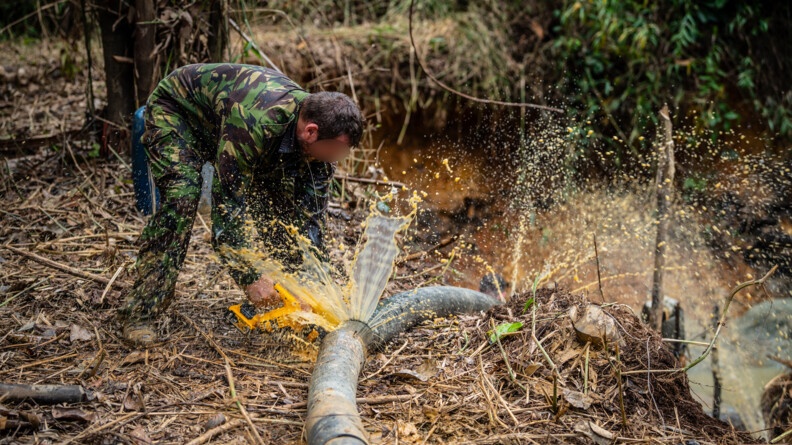 Un militaire de l'AGIGN découpe un tuyau à la scie.