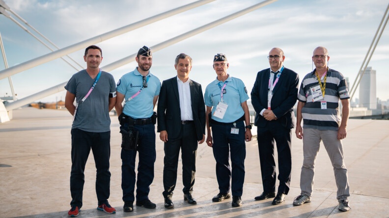 Sur le toit du Stade de France, quatre hommes (deux en tenue de gendarme, les deux autres en tenue civile) posent avec Gérald Darmanin, ministre de l'intérieur et des outre-mer, et Laurent Nuñez, préfet de police de Paris