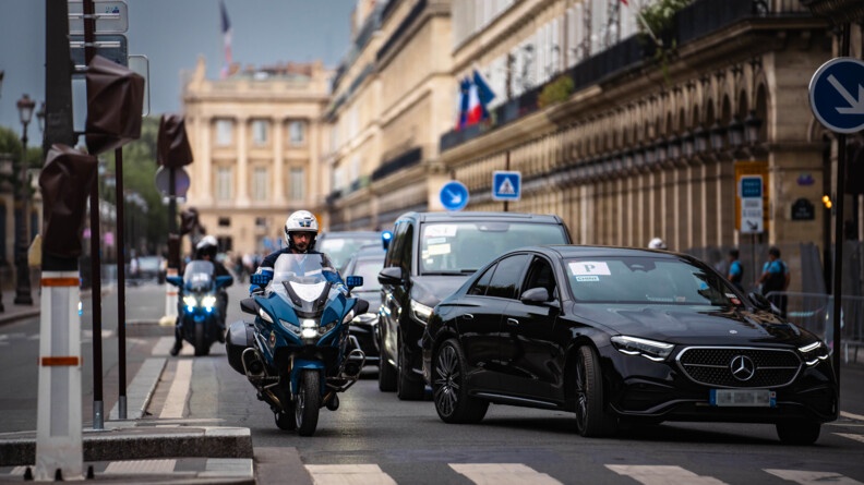 Un motard de la garde républicaine en escorte aux côté de plusieurs véhicules noirs