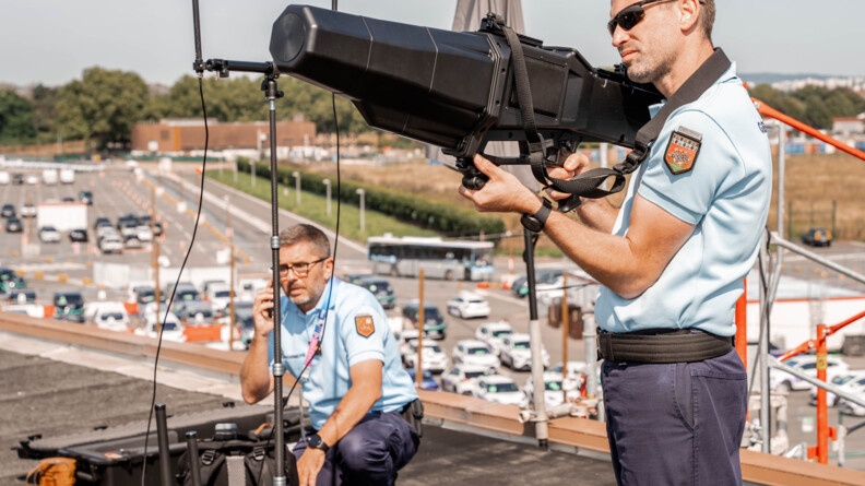 Un gendarme visant un drone avec un fusil anti-drones sur le toit du village média.