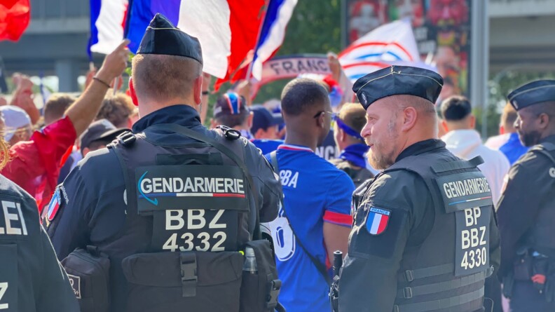 Deux gendarmes de l'UOFA, à leur gauche l'épaule d'un policier allemands, devant la foule des supporters de football