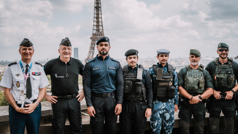 Le directeur général de la gendarmerie nationale pose aux côtés de gendarmes étranger sur le toit d'un bâtiment. On aperçoit la Tour Eiffel derrière eux.