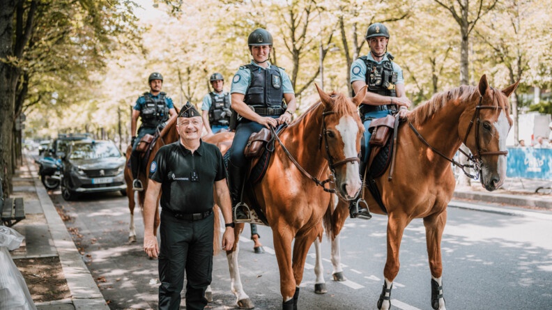 Le directeur général de la gendarmerie nationale pose, souriant, aux côtés de quatre cavaliers, dans les rues de Paris