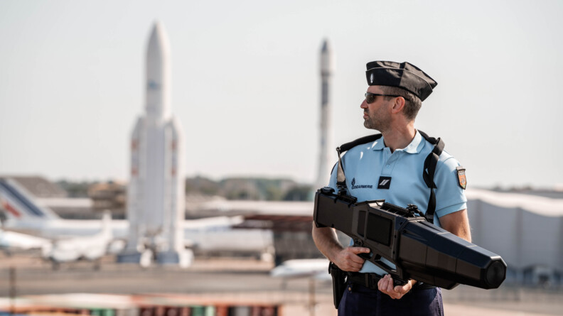 Gendarme avec fusil de brouillage positionné sur le toit du village média.