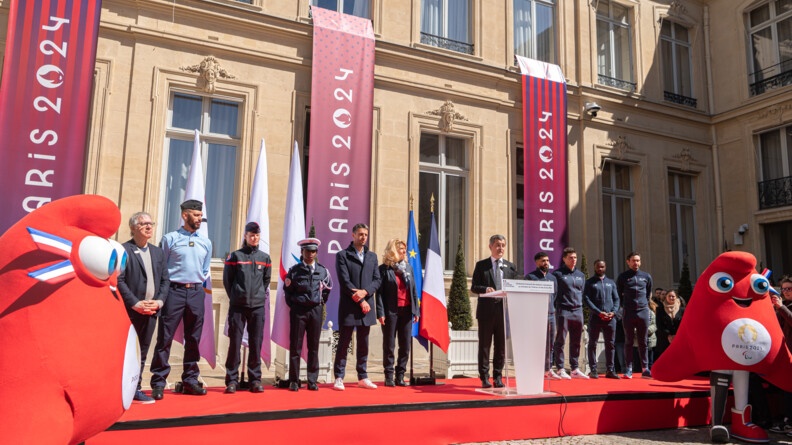 Discours du ministre de l'Intérieur et des Outre-mer devant l'hôtel de Beauvau et en compagnie des porteurs de drapeaux, de Tony Estanguet et de quelques sportifs.
