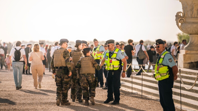 Cinq militaires de l'armée de l'air salue un gendarme, tandis que d'atres gendarmes sont en sécurisation