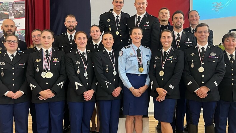 Des gendarmes, hommes et femmes, posent ensemble, souriants, en uniforme, révêtant une ou plusiers médailles autour du cou.