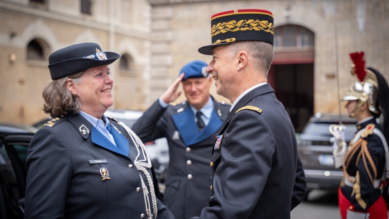 La commandante Kmar salue un haut gradé de la gendarmerie nationale dans une cour. Tous deux sont en uniforme et se sourient l'un  à l'autre