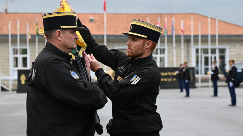 Un capitaine de gendarmerie mobile accroche le fanion au FAMAS du porte-fanion