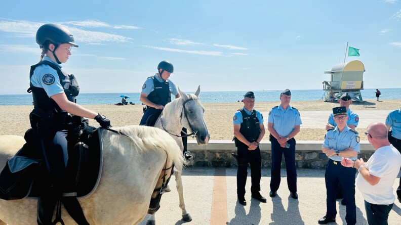 Devant la plage à Leucate dans l'Aude, le Major général de la gendarmerie échange avec plusieurs gendarmes dont deux sont à cheval.