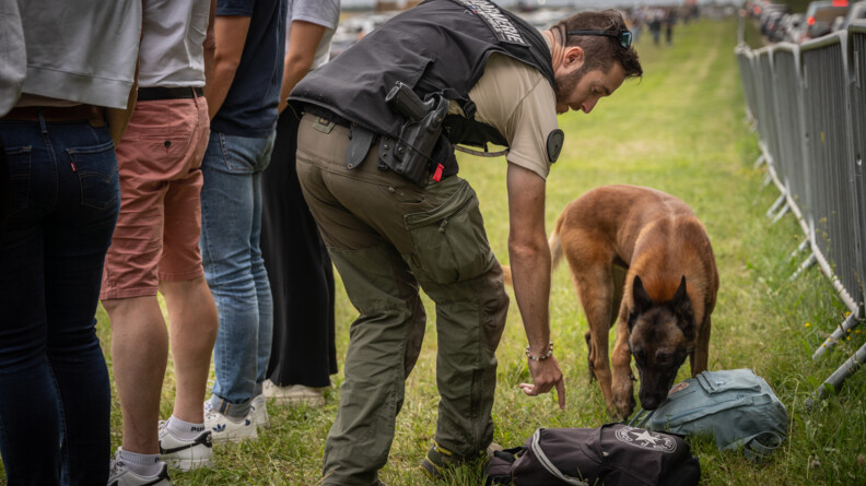 Une équipe cynophile vérifie les sacs des spectateurs autour du château de Chambord. Le gendarme pointe un sac pour que le chien le renifle.
