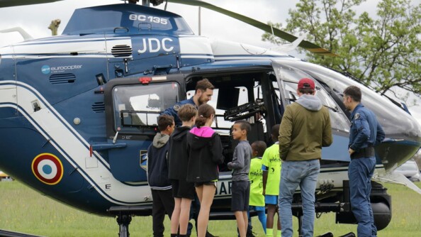 Six enfants au pied d'un hélicoptère gendarmerie avec un adulte et deux pilotes gendarmerie