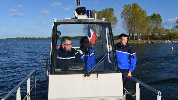 Trois gendarmes dans une embarcation sur un cours d'eau