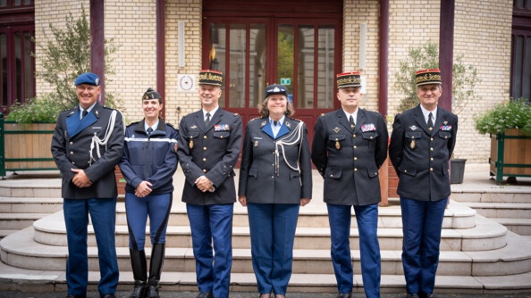 Des gendarmes en uniforme posent autour de la commandante de la KMar (Royal Netherlands Marechaussee) devant un perron. Tous sont souriants.