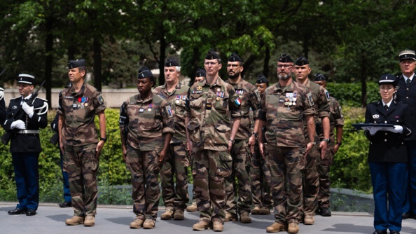 Des militaires en tenue  de camouflage se tiennent debout lors d'une cérémonie officielle