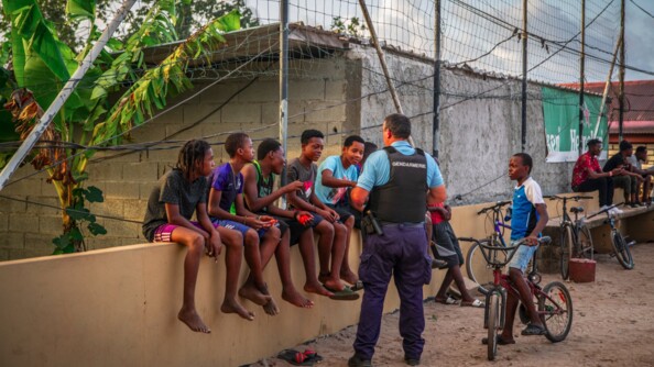 Commandant en second de la compagnie s'adressant à des enfants assis sur un mur.