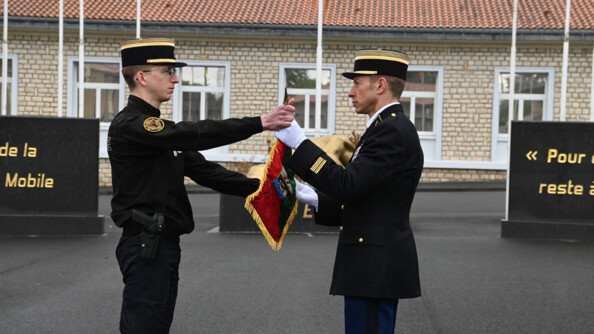 Un colonel de gendarmerie mobile remet un fanion rouge et vert à un capitaine de gendarmerie mobile
