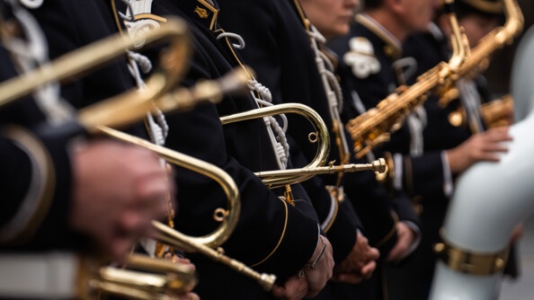 Photo prise lors d'une cérémonie officielle. On aperçoit les bras de militaires en uniforme bleu marine, avec leur instrument de musique dans les mains.