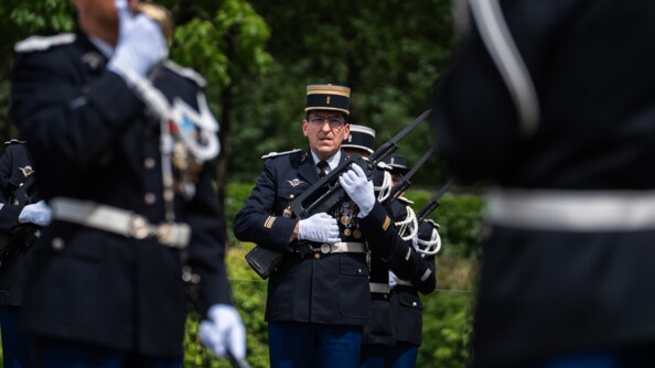 Lors d'une cérémonie officielle, des militaires se tiennent debout, avec leur arme portée contre la poitrine