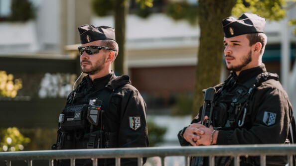 Deux gendarmes mobiles sécurisent la cérémonie. Ils sont devant une barrière.