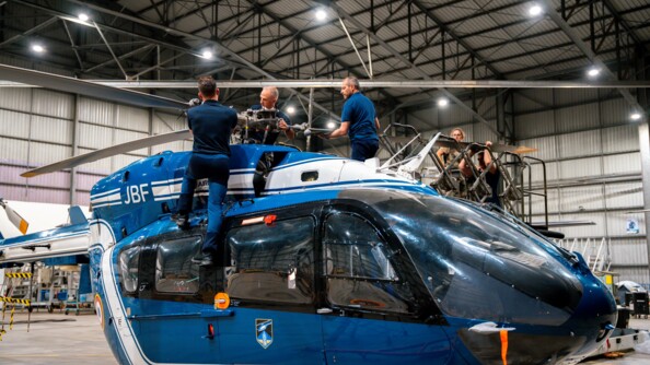 Trois gendarmes en train de monter les pales d'un hélicoptère EC145 de la gendarmerie dans un hangar